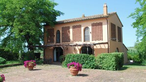 A two-story building with a brick facade, arched windows, and a covered patio area. - Pero – Two Level Apartment in Tuscan Farmhouse with Swimming Pool, 2 Bedrooms (Castelfiorentino)