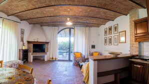 A rustic interior with a brick ceiling, a fireplace, a dining area with a table and chairs, and a kitchen area with a counter and cabinets. - Pero – Two Level Apartment in Tuscan Farmhouse with Swimming Pool, 2 Bedrooms (Castelfiorentino)