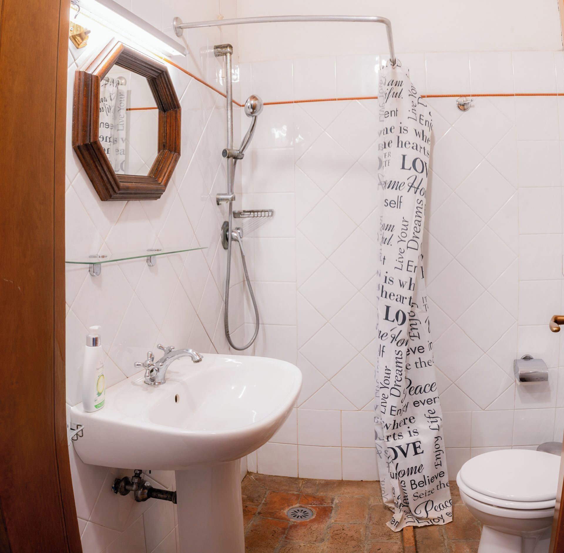 A bathroom with a white sink, a mirror, a shower, and a toilet.