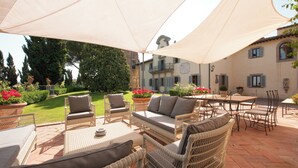 Un patio al aire libre con mobiliario de mimbre, una mesa y sillas bajo un dosel grande.