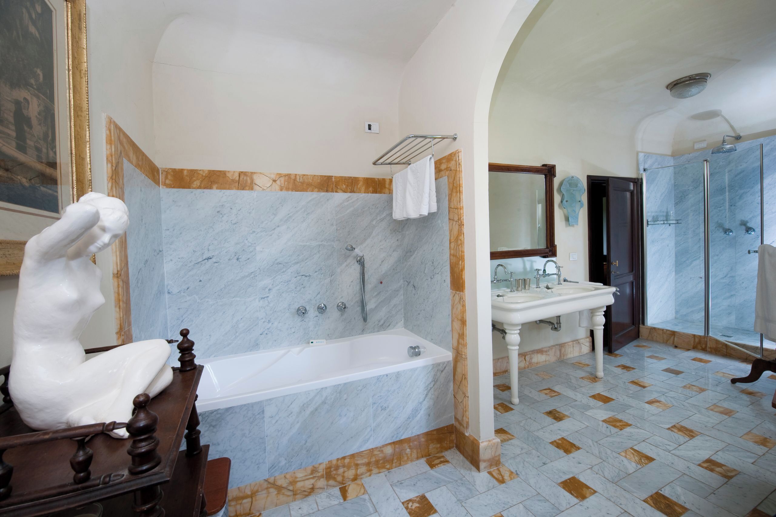 Ein geräumiges Badezimmer mit einer Marmorbadewanne, einer separaten Duschkabine und einem klassischen Waschbecken.