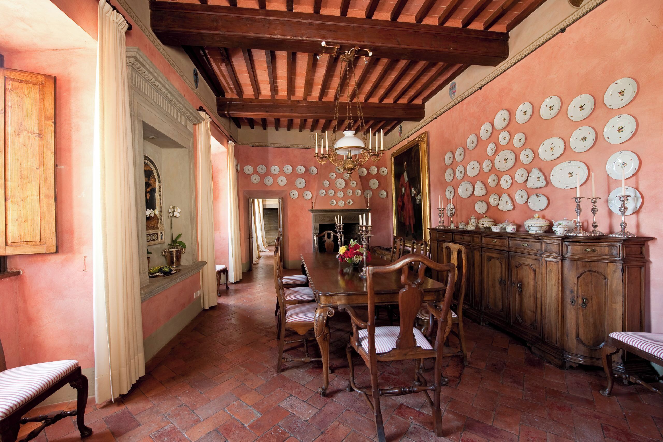 Un comedor con una mesa y sillas de madera, un espejo grande y una pared decorada con numerosas placas.