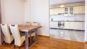 A modern kitchen with wooden cabinets, a stainless steel oven, and a dining area with a wooden table and chairs. - AMBER apartments Large & Cozy Flat SIBIU  #24 (Sibiu)