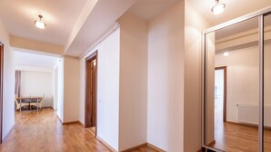 A spacious hallway with wooden flooring, a dining area with a table and chairs, and a large mirror reflecting the room. - AMBER apartments Large & Cozy Flat SIBIU  #24 (Sibiu)