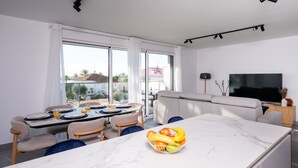 Un salon moderne comprenant un coin repas, de grandes fenêtres et un téléviseur à écran plat.