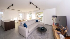 Un salon moderne avec un canapé, une table basse et un bureau en bois équipé d’un ordinateur.