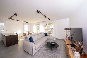 A modern living room with a sofa, coffee table, and a wooden desk with a computer. - Voiles Blanches 123 By Avecoeur (Vallauris)