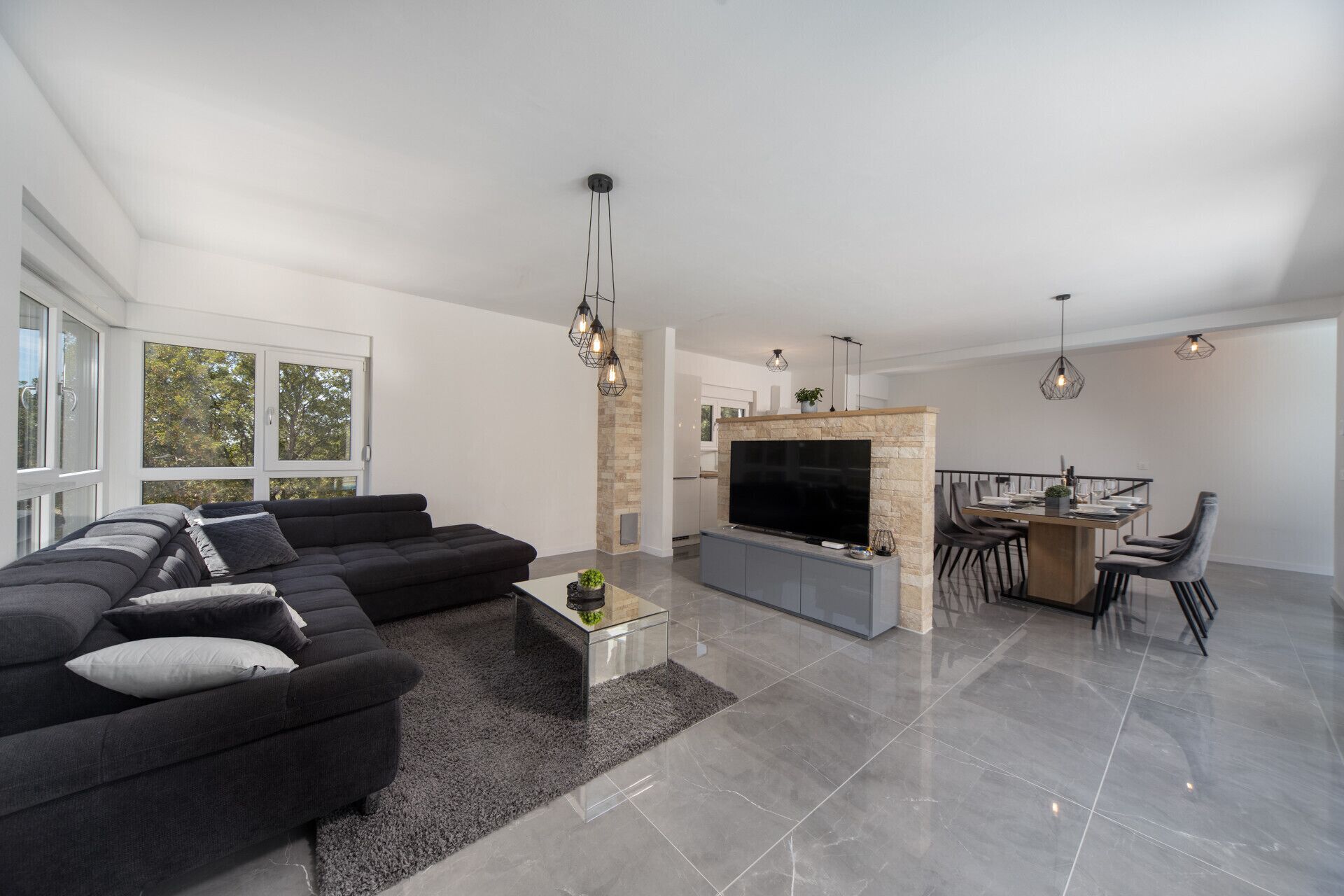 Una sala de estar moderna con un sofá modular, un televisor de pantalla plana y un comedor con una mesa y sillas.