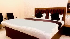A neatly made bed with a dark headboard, white bedding, and two black pillows. - Hotel Shree Kanhaiya Palace vrindavan  (Vrindavan)