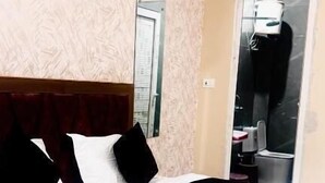 A hotel room with a bed, a mirror, a door, and a window. - Hotel Shree Kanhaiya Palace vrindavan  (Vrindavan)