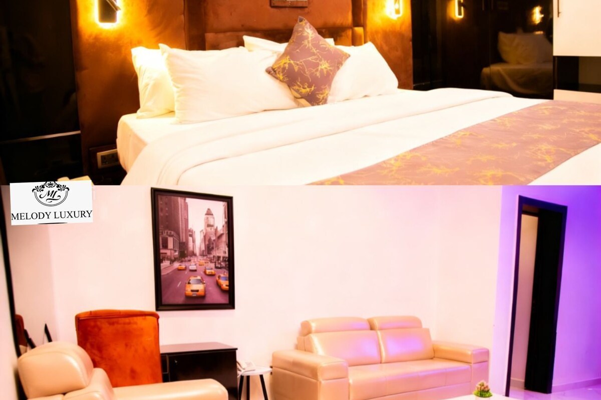 A hotel room with a bed, a sofa, a coffee table, and a framed cityscape picture on the wall.