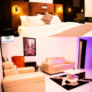 A hotel room with a bed, a sofa, a coffee table, and a framed cityscape picture on the wall. - Melody Luxury (Lekki)