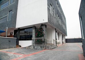 A modern building with a white facade and a large entrance. - Melody Luxury (Lekki)