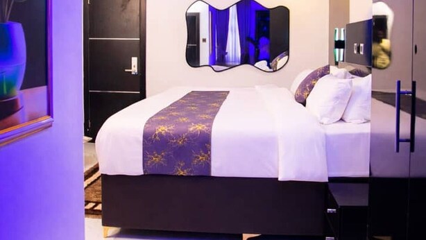 Een moderne slaapkamer met een bed, een grote spiegel en een deur.