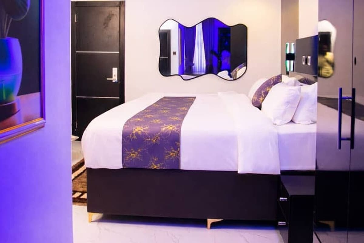 A modern bedroom with a bed, a large mirror, and a door.