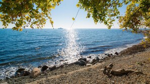 A rocky beach with a clear view of the sea and a ship in the distance. - Sunday Resort Rugen 2-bedroom Suite (Sagard)