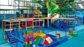 An indoor play area with various play structures, including slides and climbing frames.