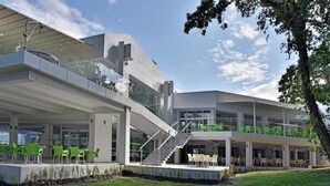 A modern building with a glass facade, outdoor seating area, and a staircase leading to an upper level. - VILLAS HOLIDAYS (Kiten)