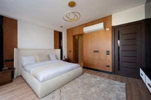 A bedroom with a large bed, wooden panel walls, a ceiling light fixture, and a wardrobe.