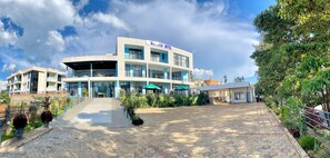 A modern hotel with a central courtyard, outdoor seating, and a clear sky. - Ibigabiro Hotel (Kagano)