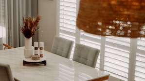 A dining table with a white marble top, surrounded by four grey upholstered chairs.
