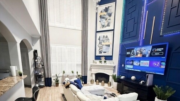 Uma sala de estar moderna com um sofá branco, lareira, televisão e um candelabro.
