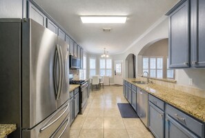 A modern kitchen with stainless steel appliances, granite countertops, and a central island. - Private Pool 4BR Home for 8 Near Houston and NRG (Manvel)