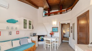 A cozy living area with a sofa, a dining table, and a kitchen in the background. - Apartment 'Trilocale Taverna 80m from Beach' with Sea View, Private Terrace & AC (Porto Taverna)