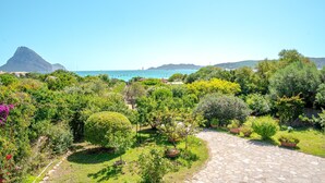 A garden with a stone pathway, various plants, and a view of the sea and mountains. - Apartment 'Trilocale Taverna 80m from Beach' with Sea View, Private Terrace & AC (Porto Taverna)
