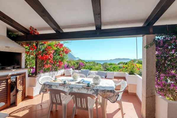 Eine Terrasss mit Esstisch, Grill und Meerblick.
