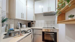 A compact kitchen with white cabinets, a stainless steel sink, a dishwasher, and an oven. - Stylish 2 bed - Tower Hamlets (Greater London)