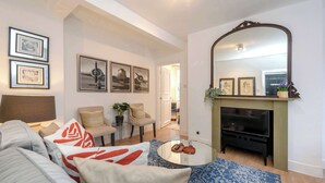 A living room with a sofa, armchairs, a coffee table, a fireplace, and framed pictures on the wall. - Stylish 2 bed - Tower Hamlets (Greater London)
