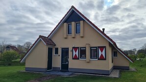 Et toetagers hus med gavl, hoveddør og en lille veranda.