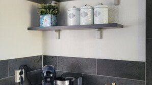 Et køkken med kaffemaskine, elkedel og en kasse Twinings te.