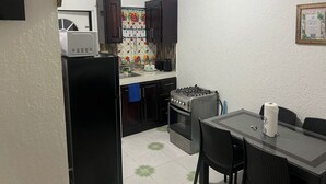 A compact kitchen with a refrigerator, microwave, stove, and oven. There is a dining table with chairs and a small window above the sink. - 1-bedroom apartment in marvelous Ocho Rios with AC comfort (Ocho Rios)