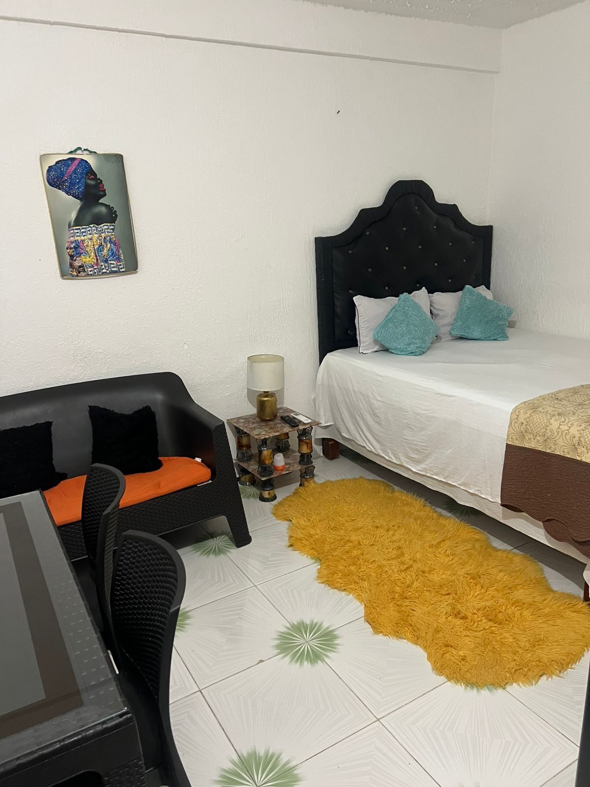 Ein Hotelzimmer mit einem Bett, einem Schreibtisch mit Computer, einem Sessel, einem kleinen Tisch mit Lampe und einem dekorativen Teppich.