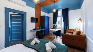 Ein Hotelzimmer mit Bett, Sofa, Schreibtisch und Fernseher.