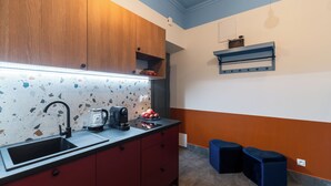 Eine Küche mit einem schwarzen Spülbecken, Holzschränken und einer Arbeitsplatte mit einer Kaffeemaschine sowie einer Obstschale.