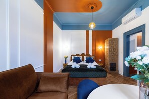 Ein Hotelzimmer mit Bett, Sofa, rundem Tisch und einer Vase mit Blumen.