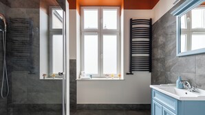 Ein Badezimmer mit Dusche, Waschbecken und Fenster.