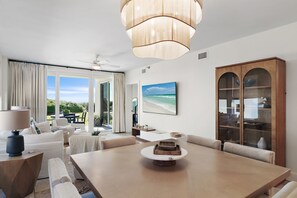 Una sala de estar moderna con una mesa de comedor, sofás, un mueble de madera grande y un ventilador de techo.