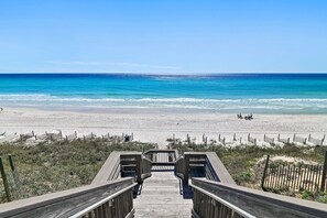 A wooden boardwalk leading to a beach with clear blue water and sandy shore. - Gulf Front Condo | Private Beach Access | Walk to Rosemary & Alys (Inlet Beach)