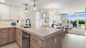 A modern kitchen with a large island, stainless steel appliances, and pendant lighting. - Gulf Front Condo | Private Beach Access | Walk to Rosemary & Alys (Inlet Beach)