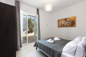 Een slaapkamer met een bed, een schilderij en uitzicht door een glazen deur.
