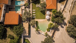 An aerial view of a property with a swimming pool, multiple lounge chairs, and a small pond. - Countryside Villa with a Walk-in Free Form Pool (Rethymno)