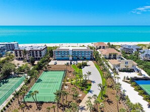 A coastal hotel with multiple buildings, a tennis court, and a beach view. - White Sands 25 | Beachfront Elegance on West Gulf Drive (Sanibel Island)