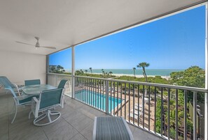 A balcony with a pool, chairs, and a view of the beach. - White Sands 25 | Beachfront Elegance on West Gulf Drive (Sanibel Island)