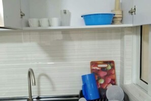 A kitchen with white cabinets, a stainless steel sink, and a blue bowl on the countertop. - Stylish 2BR Kilimani Retreat | Lift, Fast WiFi & Family-Friendly Comfort (Nairobi)