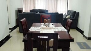 A dining area with a table, chairs, and a sofa in the background. - Stylish 2BR Kilimani Retreat | Lift, Fast WiFi & Family-Friendly Comfort (Nairobi)
