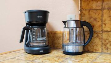 Eine Kaffeemaschine und ein Wasserkocher auf einer Küchenarbeitsplatte.